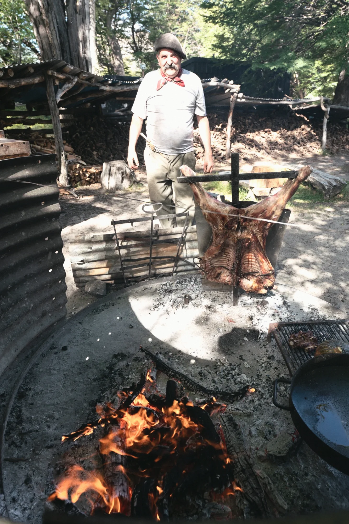 The asador beside the lamb on its cross, over the fire